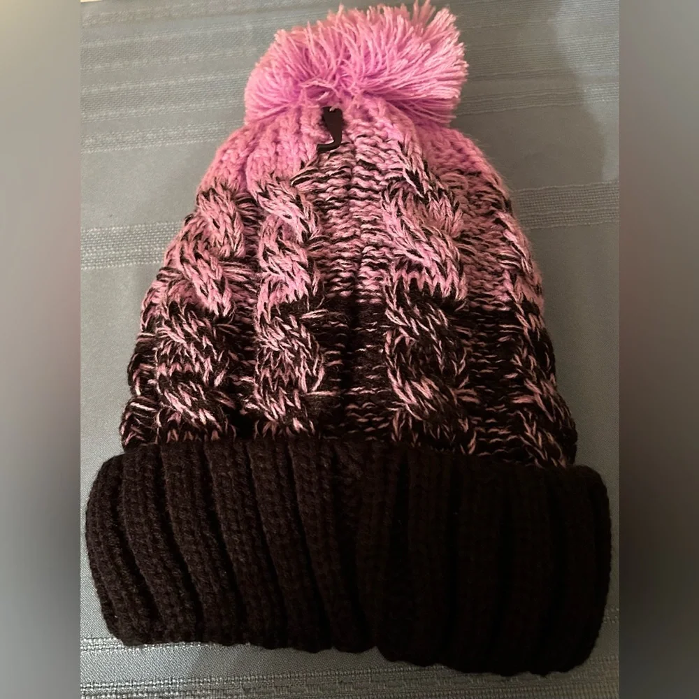 Polar Extreme cable knit beanie with a pom pom and pink and black coloring.
